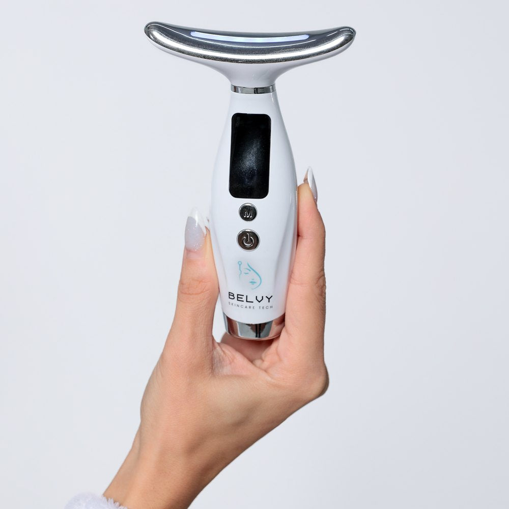 Massageador facial Glow Therapy segurado na mão, com o cabeçote curvo de metal para o contorno do pescoço